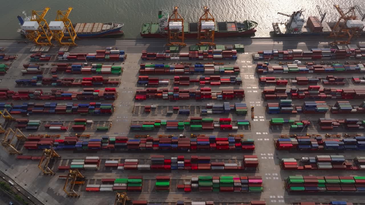 Vista aerea di un porto container trafficato con navi da carico e gru in azione.