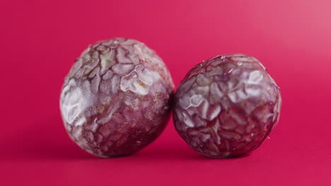 two whole avocado fruit rotating on isolated pink surface