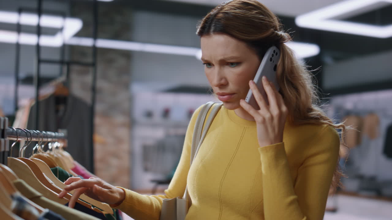 긴장 한 쇼핑 여자 가 값비싼 옷 가게 에서 휴대전화 로 전화 하고 있다