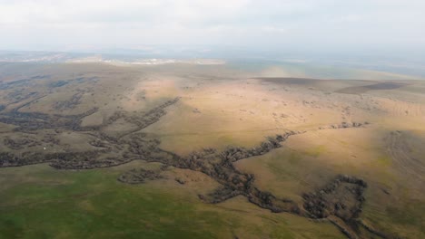 beautiful brown and green landscape of rolling hills on a sunny day - aerial, pan right shot