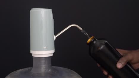 water dispenser pump wide view black background with hand filling water