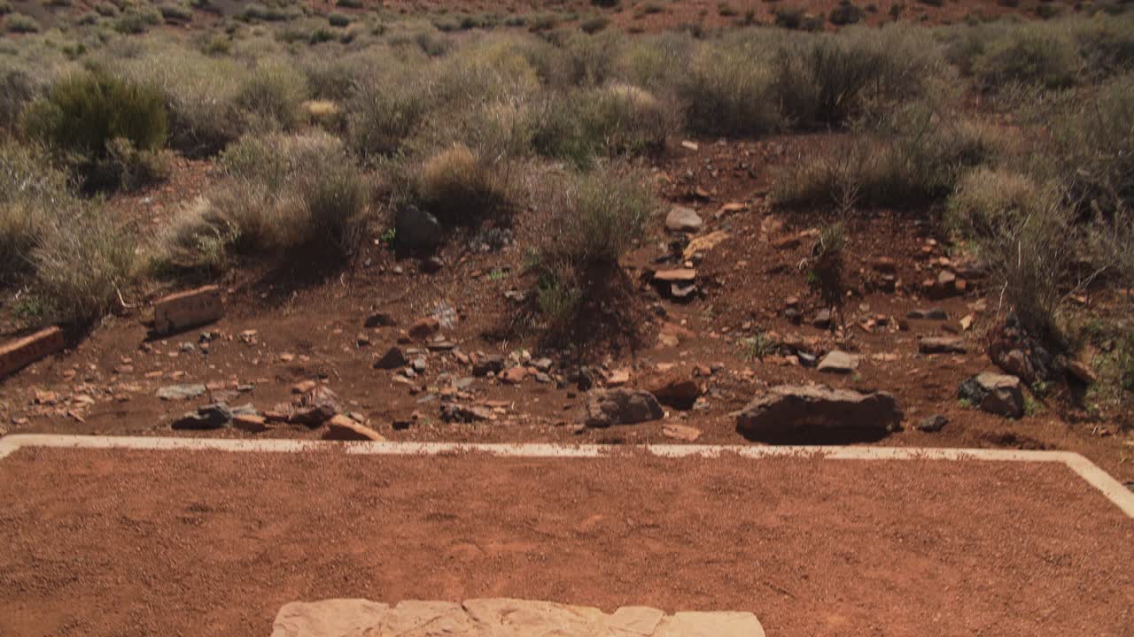 una toma en movimiento inclinada hacia abajo que pasa del paisaje desértico a una estructura de piedra llamada "espiráculo" en el monumento nacional wupatki en arizona