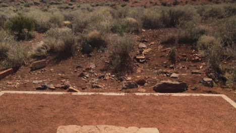 una toma en movimiento inclinada hacia abajo que pasa del paisaje desértico a una estructura de piedra llamada &quot;espiráculo&quot; en el monumento nacional wupatki en arizona