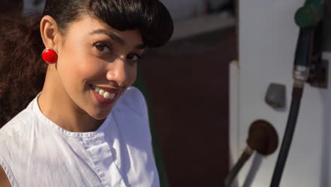 Smiling-biracial-woman-using-fuel-pump-at-petrol-station