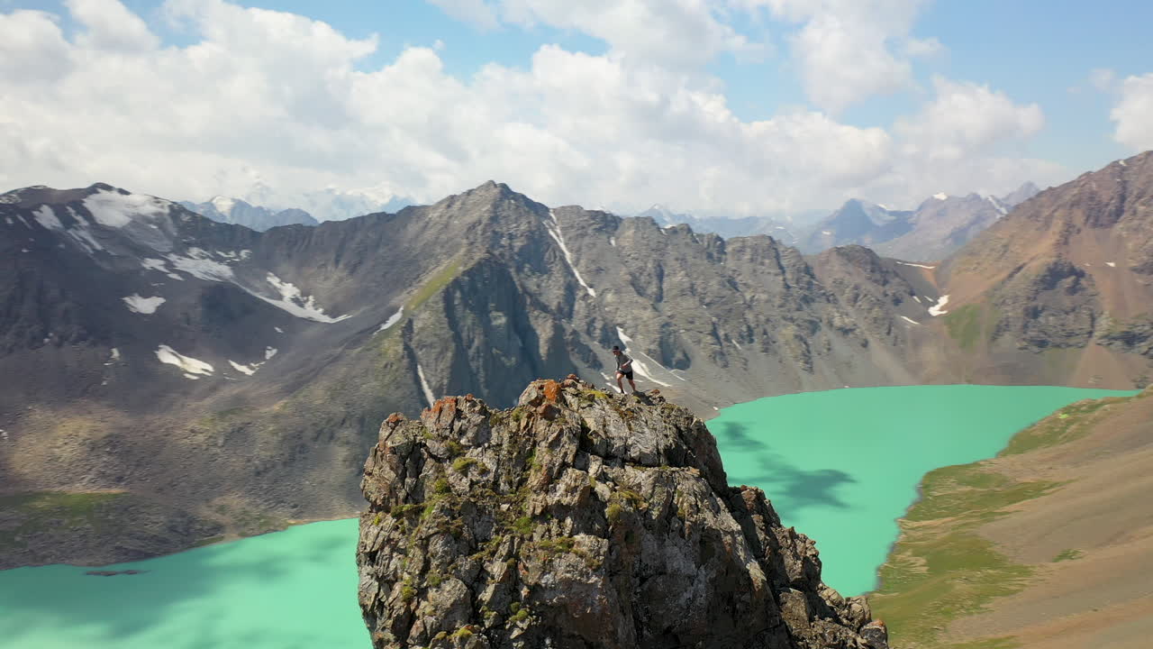 키르기스스탄의 산길에서 알라콜 호수를 바라보며 팔을 뻗은 남자, 목표, 성취, 궤도를 도는 드론