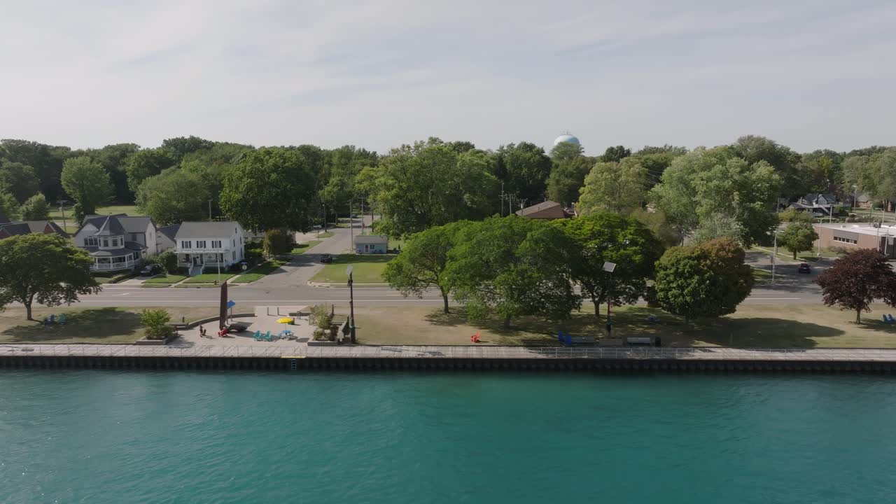 Drönarbild som långsamt flyger från vänster till höger med en medellång vy över strandpromenaden och parken i centrala Algonac, Michigan, vid Saint Clairfloden