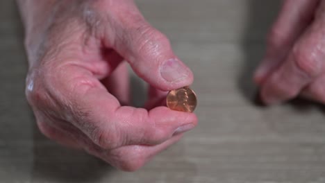 senior citizen hands pinching a penny