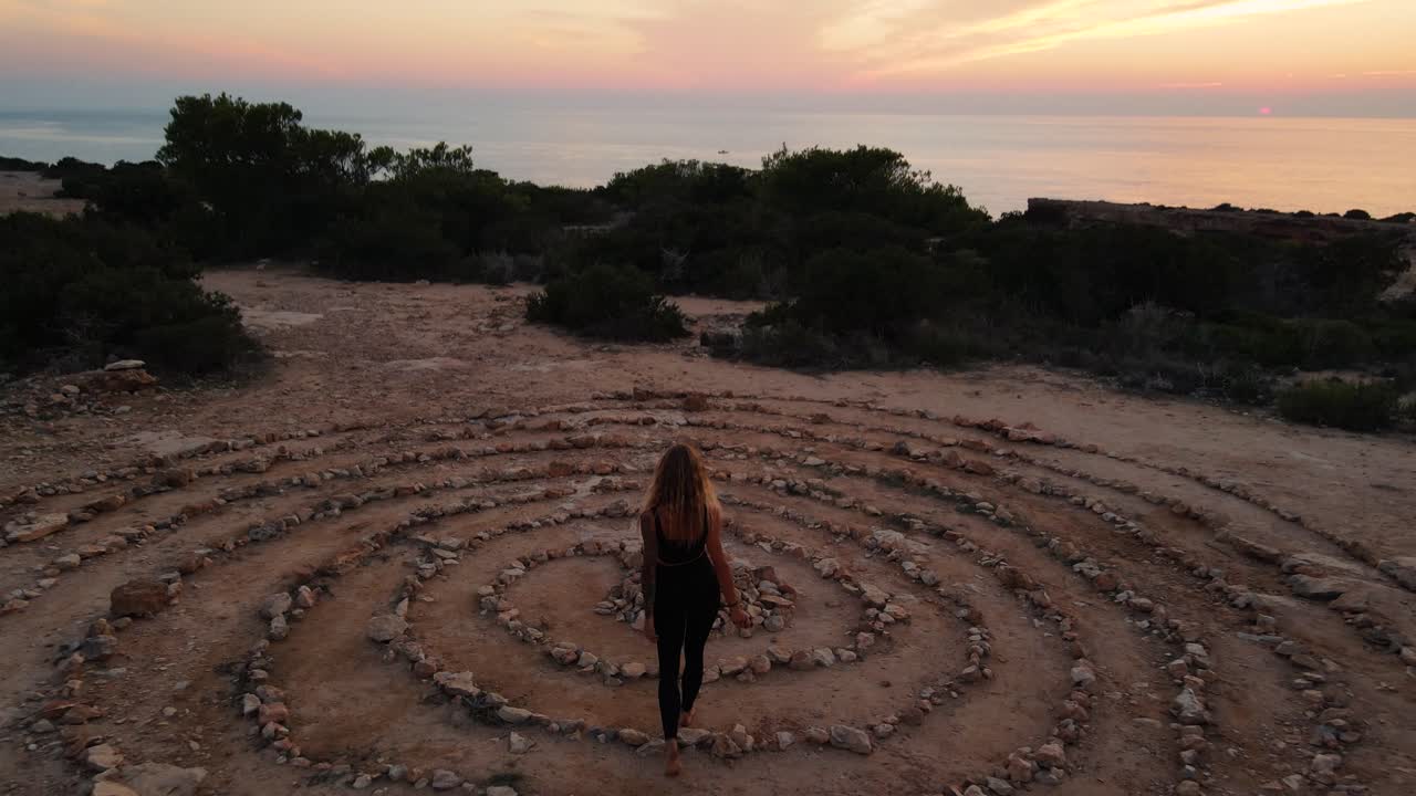 vista de dron de la mujer en el espacio del tiempo en el suelo piedras enrolladas en espiral con el cielo del atardecer