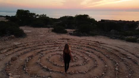 vista de dron de la mujer en el espacio del tiempo en el suelo piedras enrolladas en espiral con el cielo del atardecer