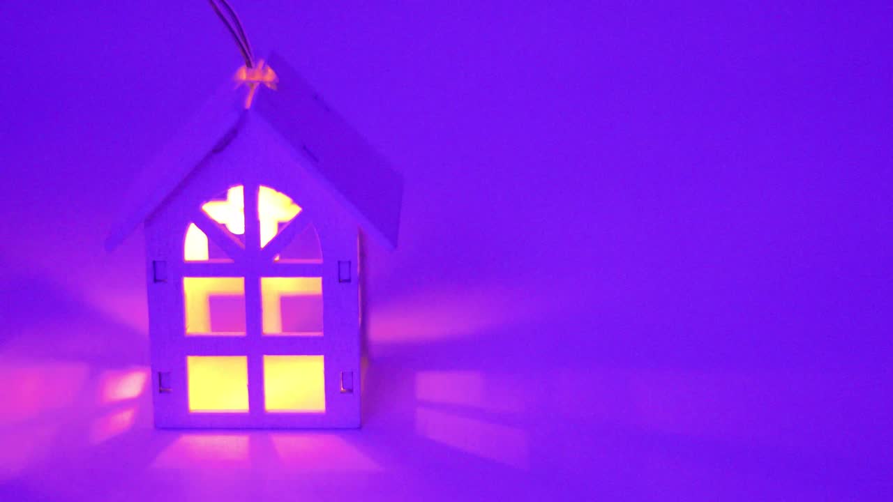 рождественская гирлянда с деревянным домом и светящимися окнами внутри на фиолетовом фоне, финансовый кредит и коммерческая недвижимость,