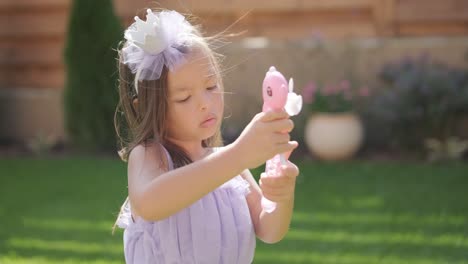 a little girl in a dress is blowing soap bubbles in the backyard on a sunny summer day