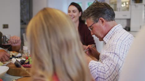 Happy-caucasian-grandfather-smiling-to-granddaughter-at-table-during-family-meal