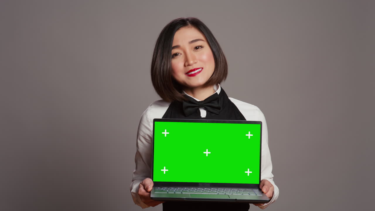 아시아 서버가 스튜디오에서 노트북에서 그린스크린 디스플레이를 보여줍니다.