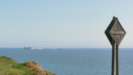 Estático-De-Mano,-Cable-De-Telégrafo-Que-Advierte-Un-Cartel-De-Madera-Con-Vistas-Al-Océano-Mientras-El-Barco-Pasa