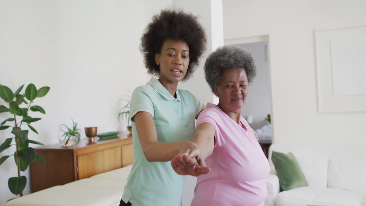 Fisioterapeuta afro-americana feliz ajudando paciente idosa a se exercitar em casa