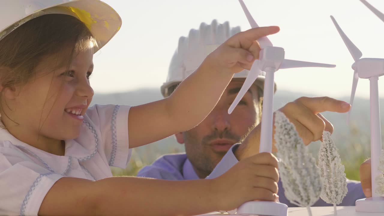отец-инженер показывает своей дочери свой проект по строительству ветряной электростанции. дочь интересуется возобновляемой энергией.