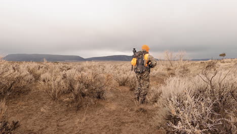 approaching a hunter in camouflage walking with his rifle ready