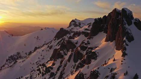 Golden-sunset-over-snow-covered-Ciucas-Mountains,-casting-warm-hues