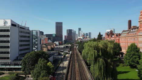 aerial drone flight along train track from piccadilly to oxford road train station giving a skyline view of elizabeth tower