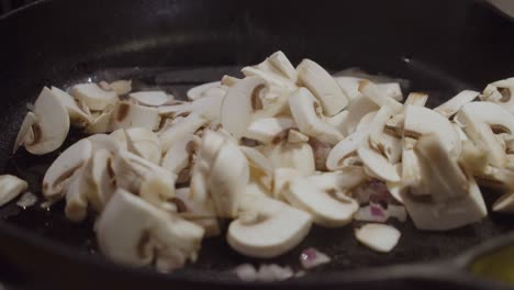 chef adds white mushroom into hot frying pan