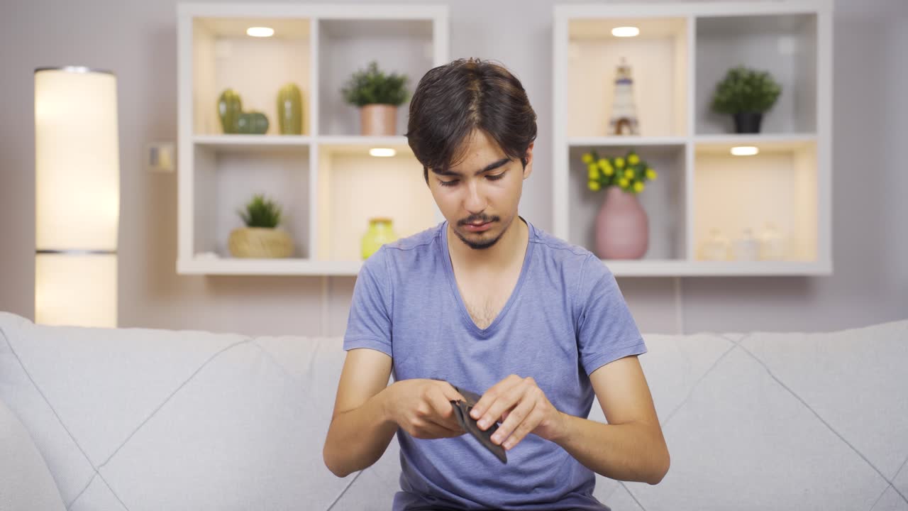 Penniless man looking at his empty wallet.