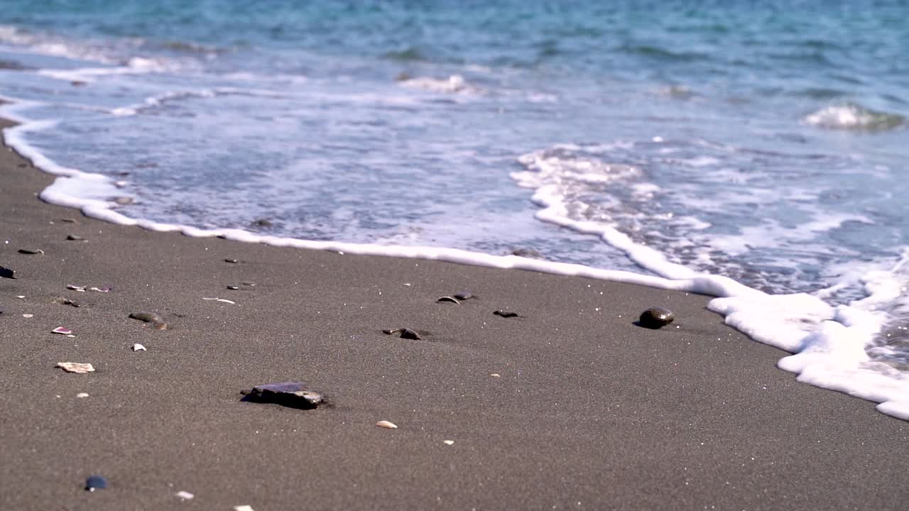 모래 해변에서 자갈을 움직이는 작은 파도
