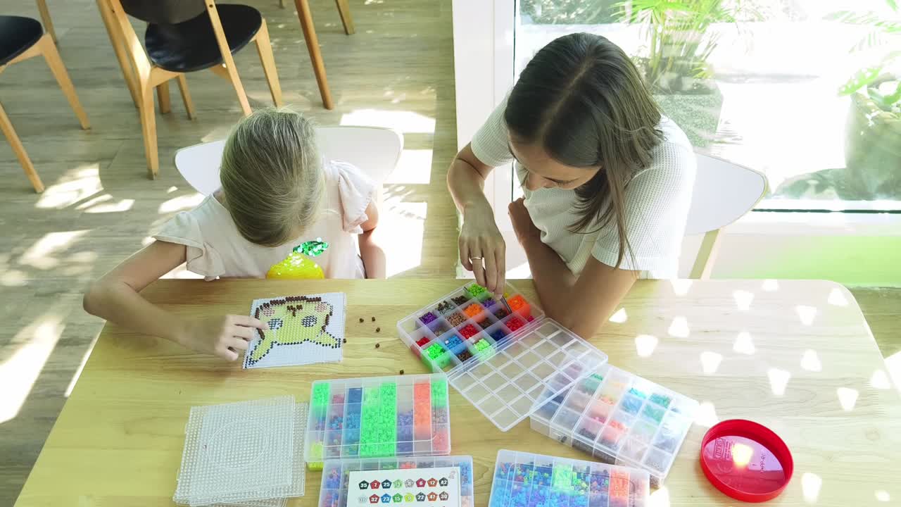 madre e hija haciendo una artesanía de cuentas