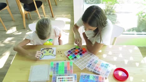 madre e hija haciendo una artesanía de cuentas