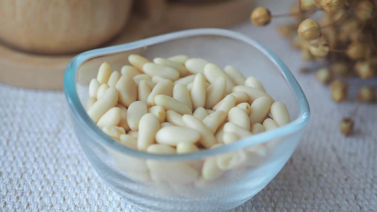 A close-up view of a glass bowl filled with pine nuts