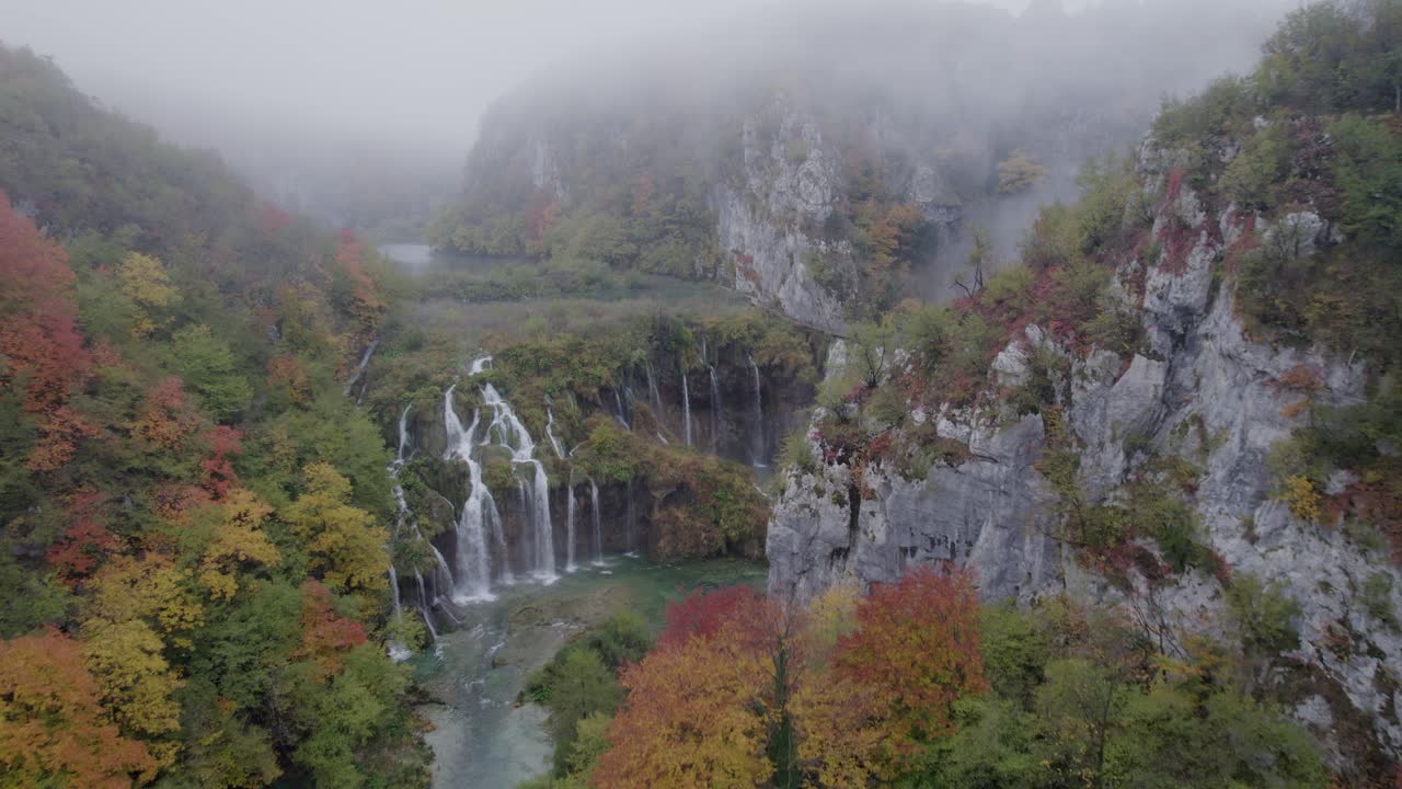 Ripresa con drone di una cascata naturale e un lago avvolto nella nebbia nel Parco di Plitvice, Croazia