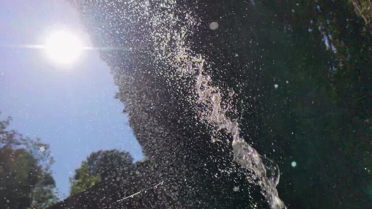 Slow Motion Hose Water and Sun Flare in Garden on Hot Sunny Day Wales UK