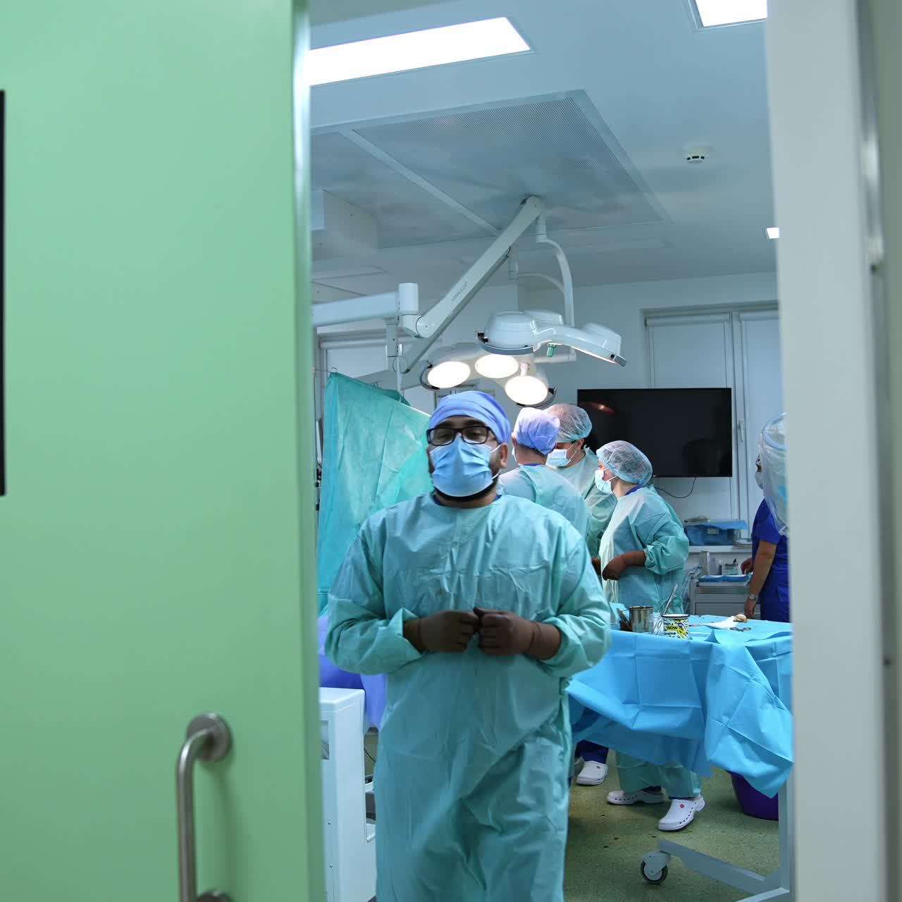 Footage at the doors of modern surgery room with medical personnel inside. Surgical operation conducted by the big team. One of the doctors leaving the operational room