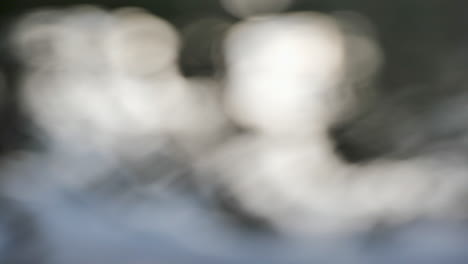 blurred water reflections with soft focus and light bokeh in slow motion, creating an abstract and dreamy visual of rippling light patterns.