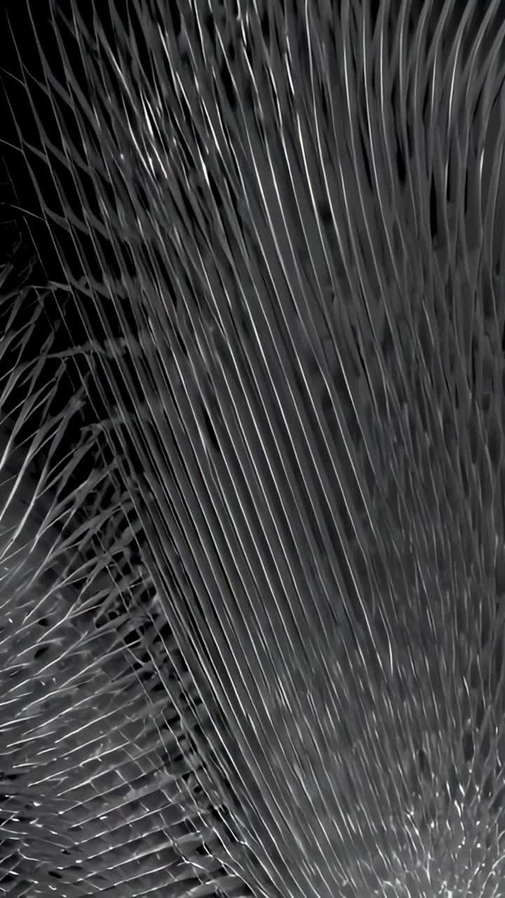 Vertical video: Shifting pleated ribbed surface revealing shadowed gaps in studio, specular glints