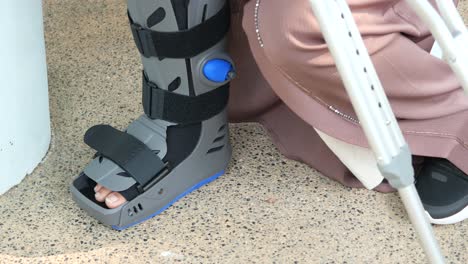 Frauen-Gebrochene-Füße-Mit-Einem-Grauen-Plastikstiefel-Knöchelbandage-Verletzungsschutzstiefel,