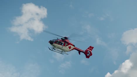 medical air rescue helicopter flying in blue sky with white clouds - slowotion sunny day