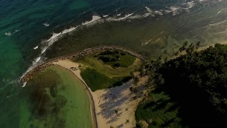 drone aéreo disparado lentamente descendiendo por la península de miami beach mientras las olas se aplastan en sus costas en itea, en el centro de grecia