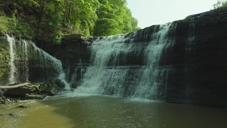slow motion pan right shot of the powerful upper balls falls cascading over rocks on a summer day