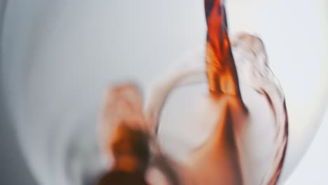 macro shot of red wine splashing into the bottom of a glass, elegant flow, white background, highspeed, slowmotion