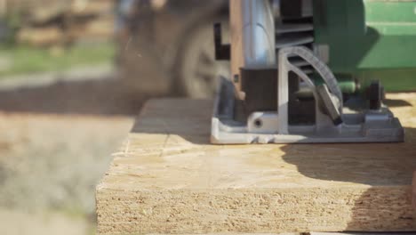 handheld circular saw cutting oriented strand board on construction site