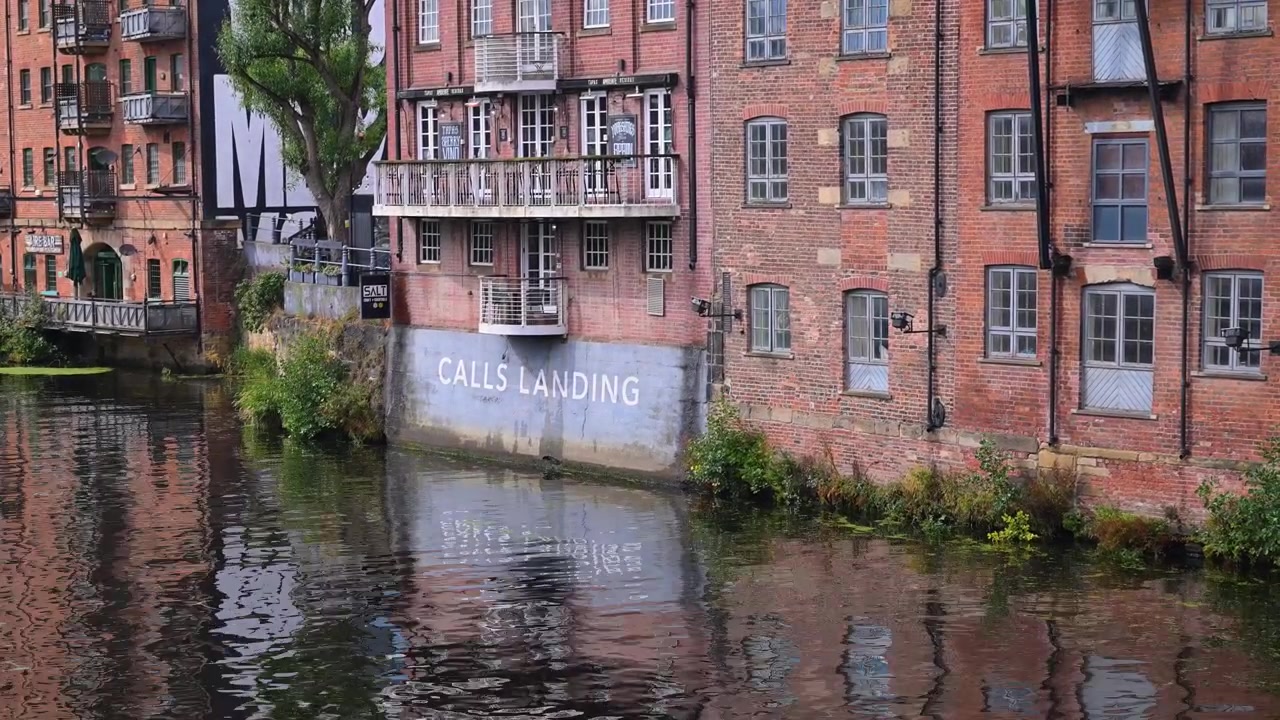 Historisches Backsteinlager und Bar am Calls Landing liegt am Fluss, dessen ruhiges Wasser Fenster, Balkone und bemalte Schilder reflektiert.