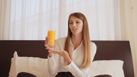 woman drinking orange juice in bed