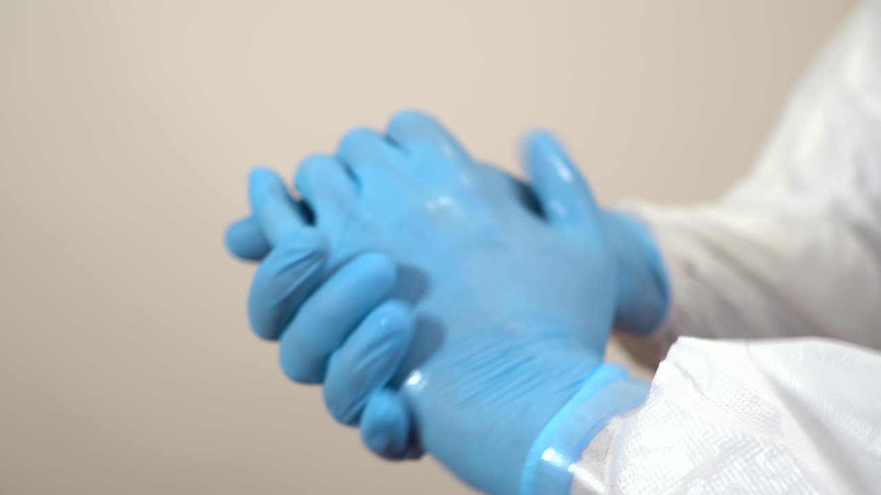 doctor hands dressed in ppe suit cleaning with gel