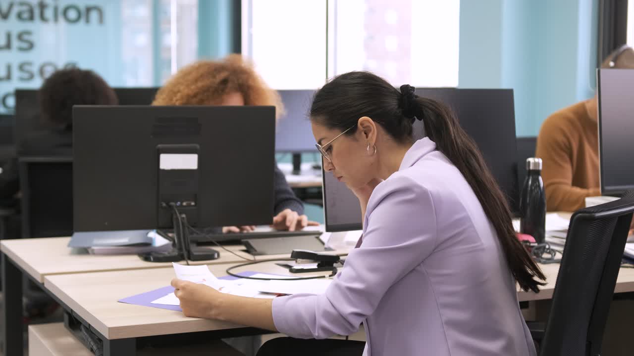 Opptatt forretningskvinne analyserer data på dokumenter på en coworking-arbeidsplass