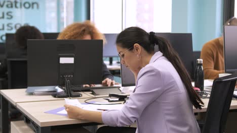 busy businesswoman analyzing data on documents at coworking workspace
