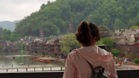 woman with a serious expression looks back over her shoulder in fenghuang ancient town