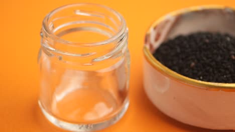 black cumin oil being poured into a small jar