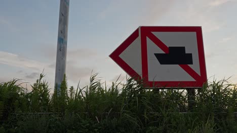 a close-up shot of a "no boats allowed" sign next to a river with reeds in the foreground