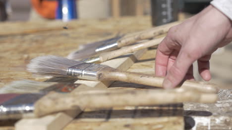 a painter picking up a brush at a construction site, close up slow motion