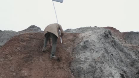 person climbing a hill with a flagpole